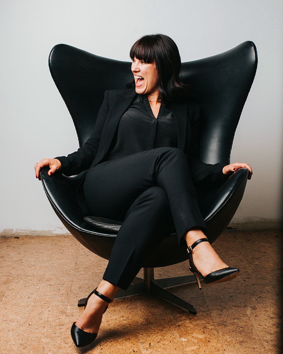 Chrystal Clifton laughing in a black leather lounge chair