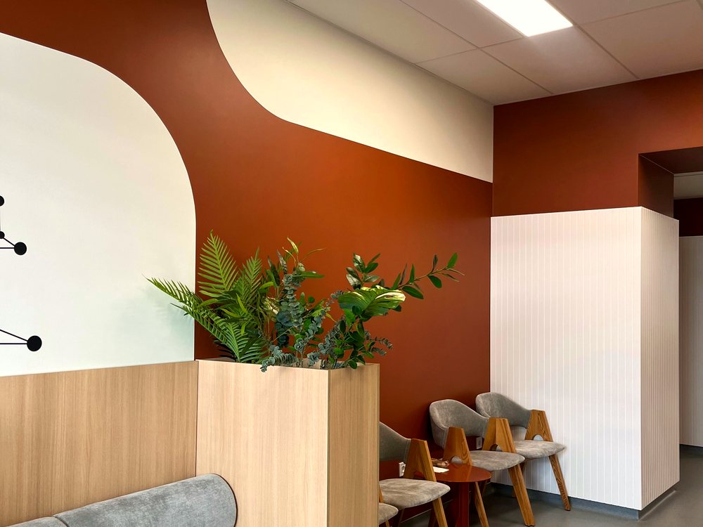 A warm clinic waiting area with wood, plants and soft seating
