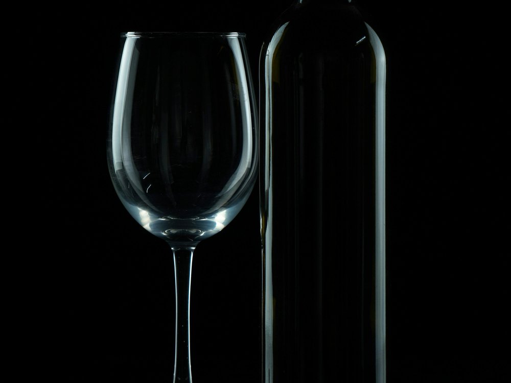 A wine glass and bottle on a dark table