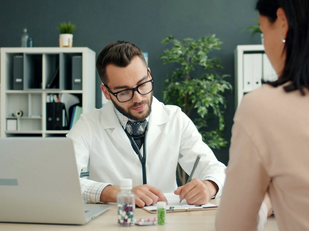 A practitioner consulting with a client at a desk in a bright office