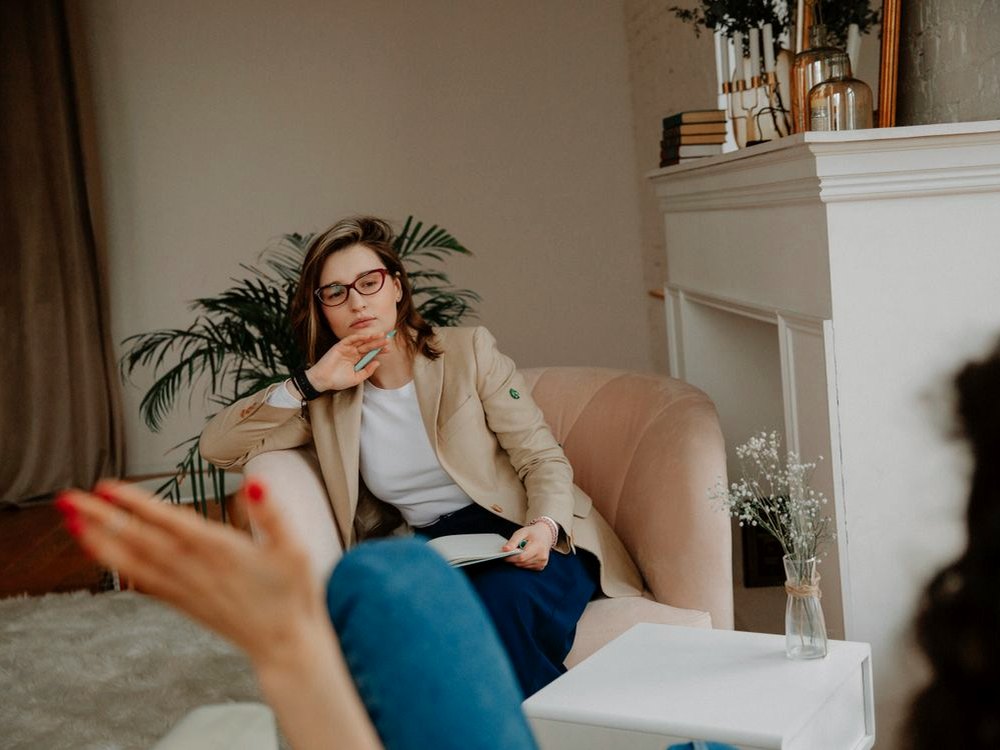 A practitioner listening to a client in a warm neutral room