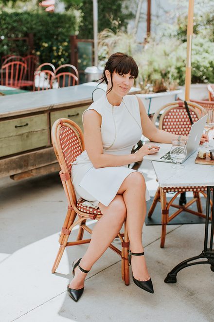 Chrystal Clifton seated at a café table with her laptop